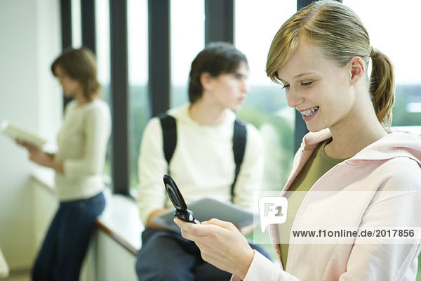 Female college student looking at cell phone  smiling