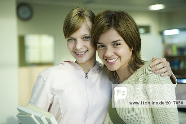 Two female college students  one with arm around the other's shoulders  smiling at camera  portrait