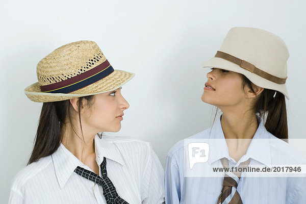 Zwei junge Freundinnen mit Hüten und Krawatten  die sich anschauen  Porträt