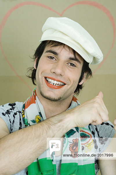 Junger Mann mit Lippenstift  Mütze und Schal  lächelnd vor der Kamera  Portrait