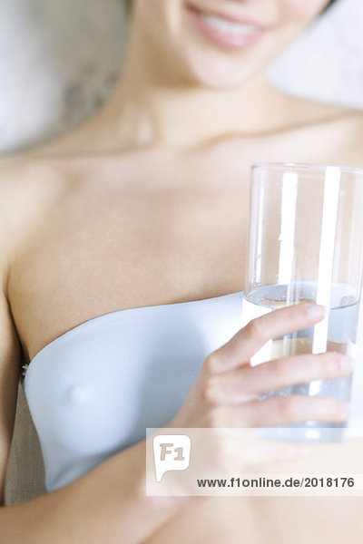 Ausschnitt einer Frau mit Wasserglas  bekleidet mit Tubetop
