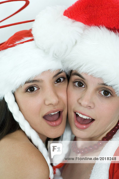 Zwei junge Freundinnen in Weihnachtskostümen  Wange an Wange  Blick in die Kamera  Porträt