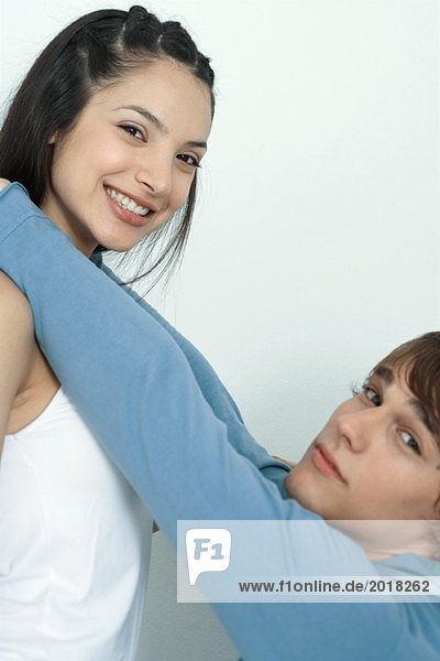 Young couple  man reaching up to put arms around woman's neck  portrait