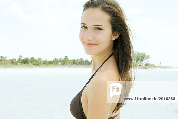 Junge Frau lächelt über die Schulter  trägt Bikini  Portrait