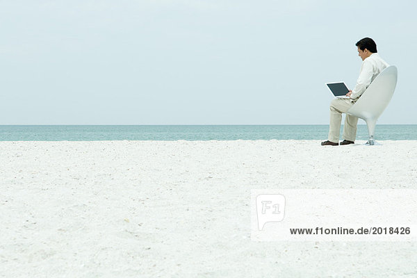 Mann mit Laptop am Strand  volle Länge