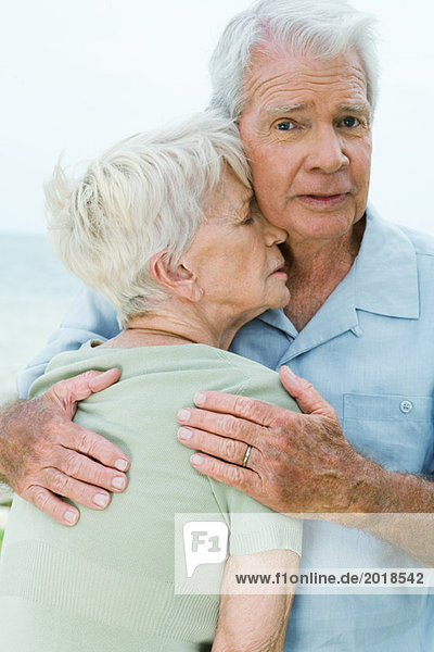 Seniorenpaar  Mann hält Frau fest gegen ihn  schaut in die Kamera