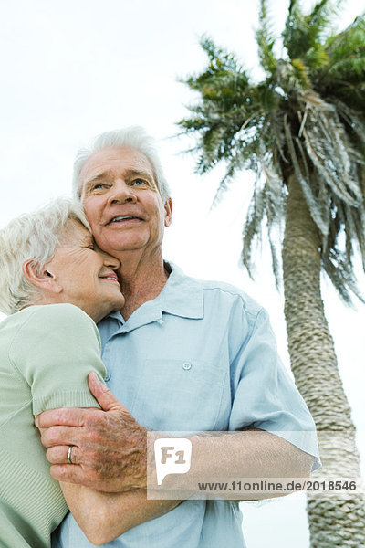 Seniorenpaar lächelnd und nuschelnd  Palme im Hintergrund  Blickwinkel niedrig