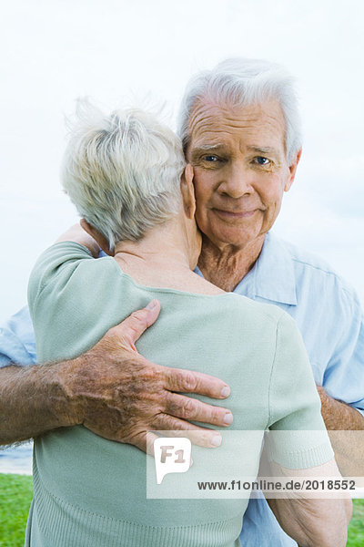 Seniorenpaar umarmt  Mann schaut in die Kamera