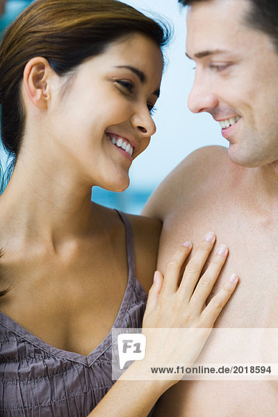 Couple smiling at each other  woman's hand on man's bare chest  close-up