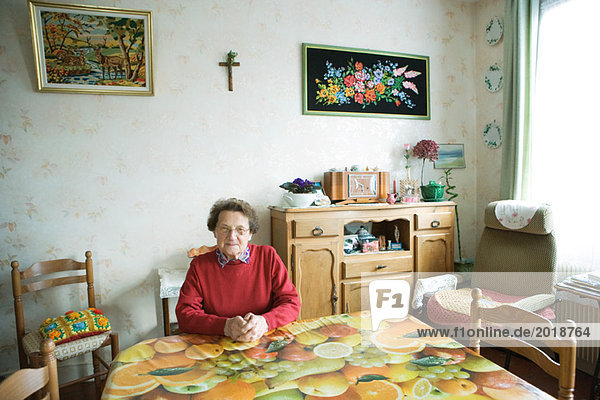 Seniorin sitzend im Hausinneren