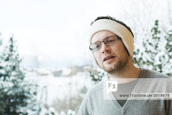 Young man wearing warm headband in snowy setting
