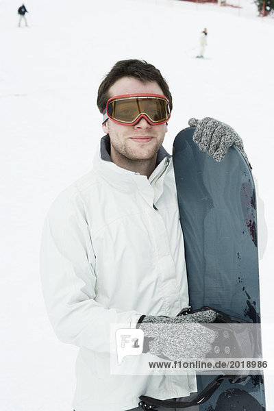 Young man standing with snowboard  portrait