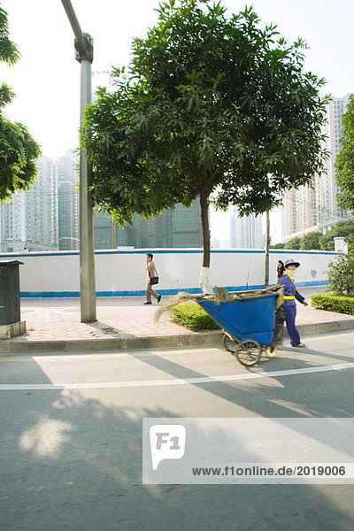 China  Provinz Guangdong  Guangzhou  öffentlicher Wartungsarbeiter zieht Mülltonne durch die Straße