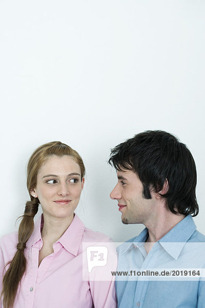 Young couple smirking at each other  head and shoulders  portrait