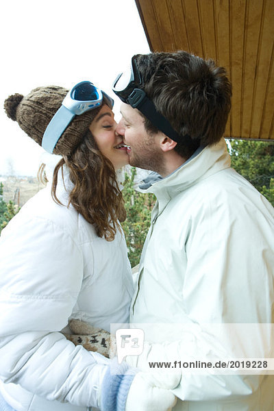 Young couple kissing  face to face  dressed in winter clothing  side view