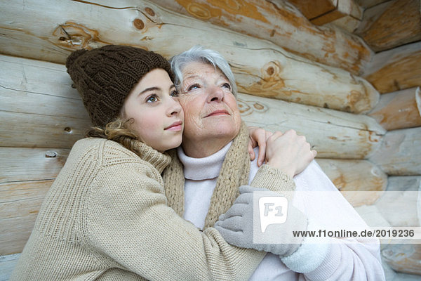 Enkelin und Großmutter umarmend  aufblickend  Portrait