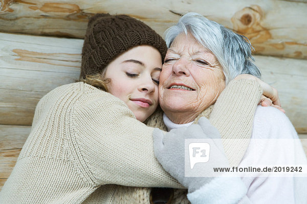 Grandmother and granddaughter embracing  eyes closed  portrait