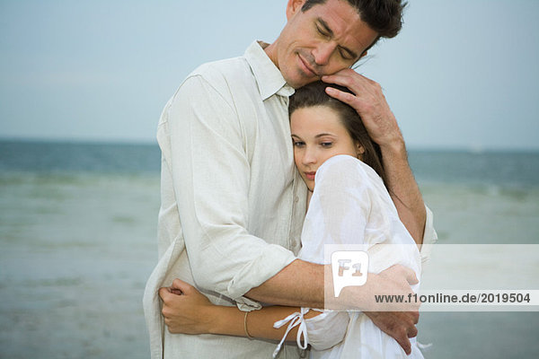 Mann und Mädchen umarmen sich am Strand  Taille oben