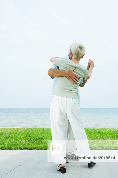 Seniorenpaar tanzt auf dem Bürgersteig mit Blick auf den Ozean  volle Länge