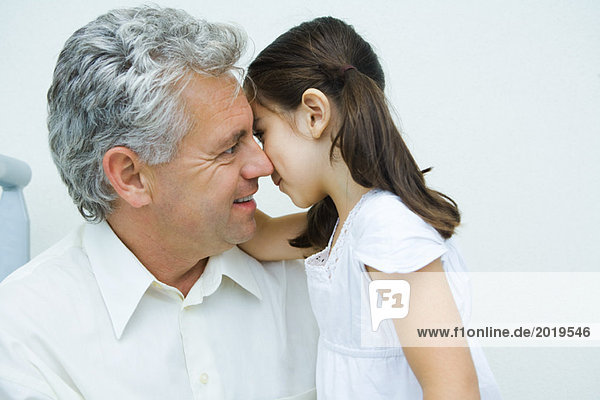 Little girl whispering to mature man  side view