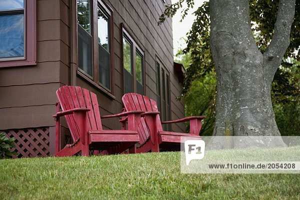 Zwei Holzstühle in der Nähe eines Baumes im Hof