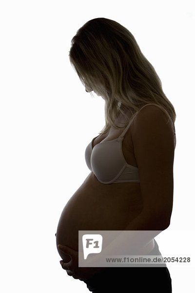 Silhouette einer schwangeren Frau  die ihren Unterleib berührt.