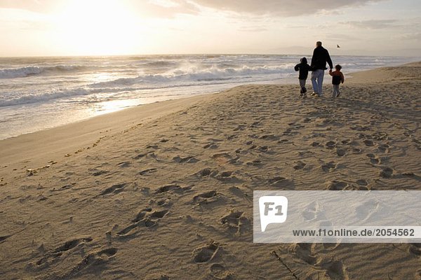 Eine Familie  die am Strand spazieren geht.