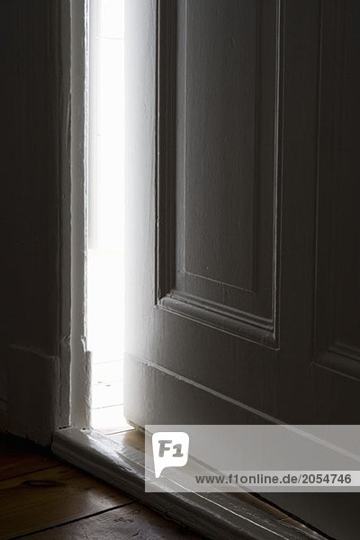 Licht  das durch eine Tür leuchtet  die einen Spalt offen ist.