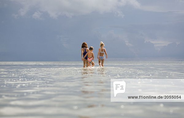 Rear view of three young girls standing in the sea