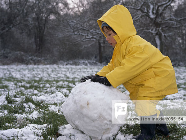 A young boy making a snowman