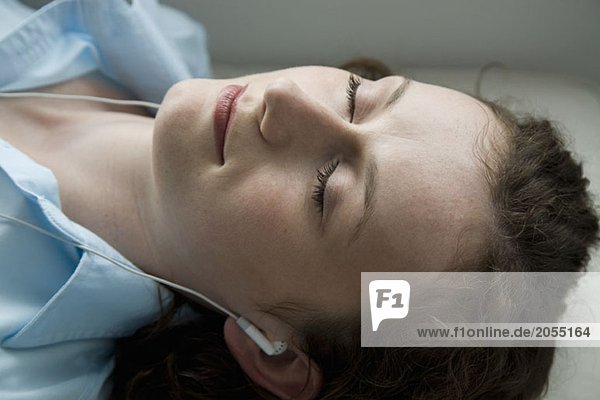 A young woman lying down whilst wearing headphones