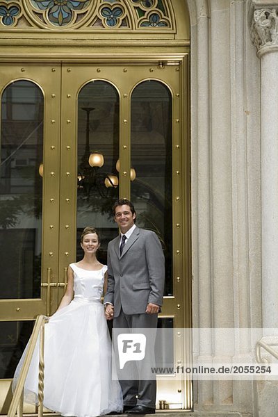 A bride and groom posing in front of a building
