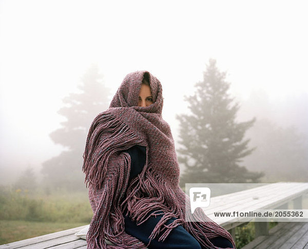 A woman wrapped in a shawl on a misty morning