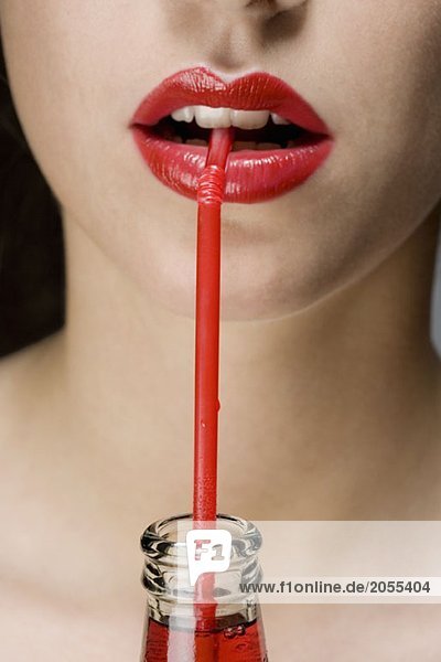 A woman wearing red lipstick drinking from a red straw
