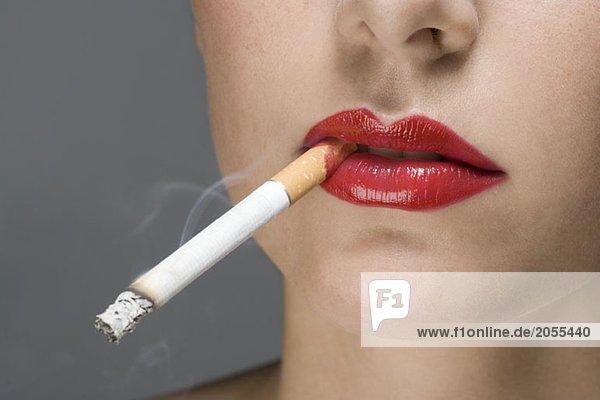 A woman wearing red lipstick and smoking a cigarette
