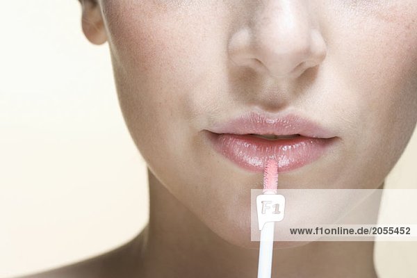 A woman applying lip gloss