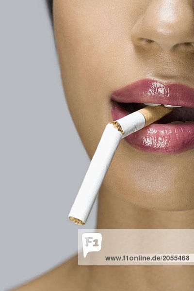 Eine Frau mit einer kaputten Zigarette im Mund.