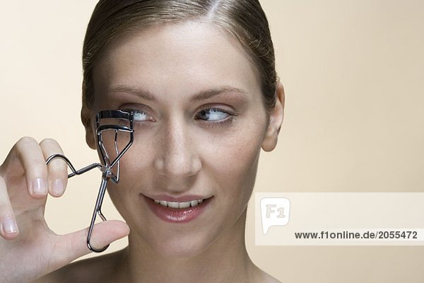 A woman using eyelash curlers