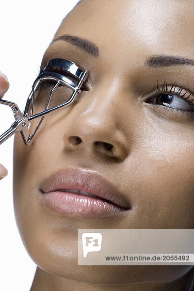 A woman using eyelash curlers