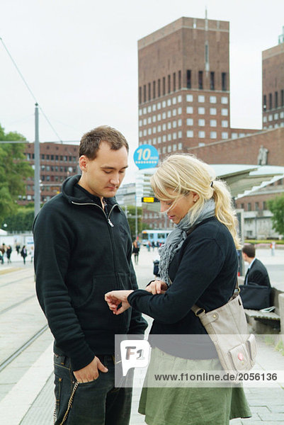 Paar schaut auf die Uhr an der Straßenbahnhaltestelle