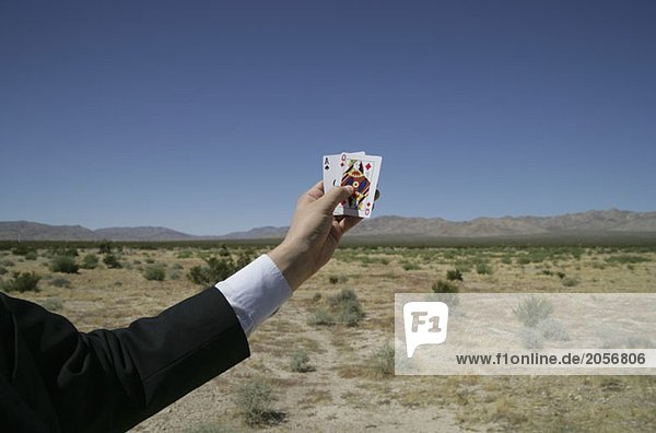 Ein Mann hält Spielkarten in der Hand in der Wüste