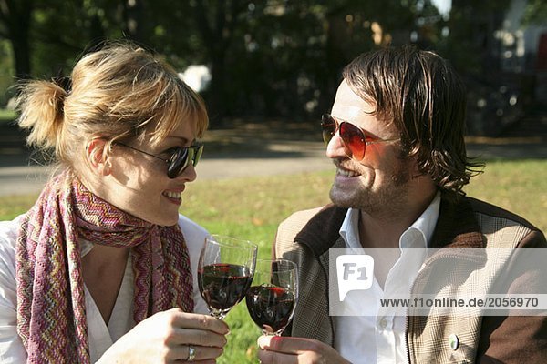 Ein junges Paar Wein trinkend in einem Park