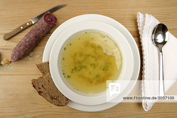 Ein Teller Suppe neben Brot und Wurst
