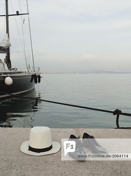 Ein Panamahut und ein Paar Schuhe am Rande eines Piers.