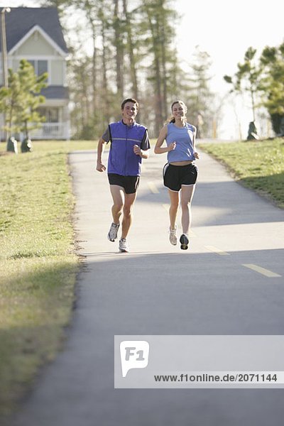 Ein Mann und eine Frau joggen die Straße entlang