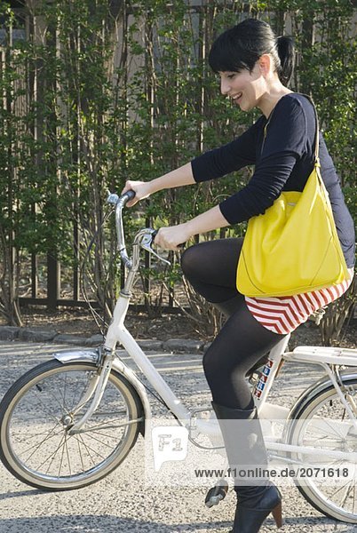 Junge Frau auf einem Fahrrad auf dem Gehweg