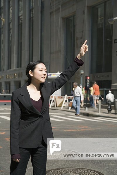 Eine junge Geschäftsfrau winkt auf der Straße ein Taxi