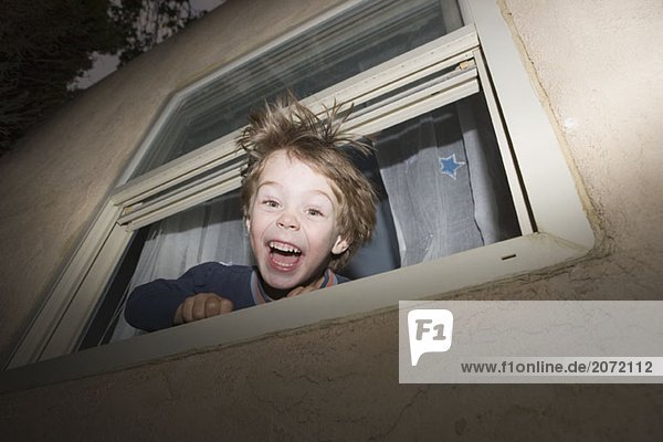 Ein kleiner Junge schaut aus dem Fenster und lacht