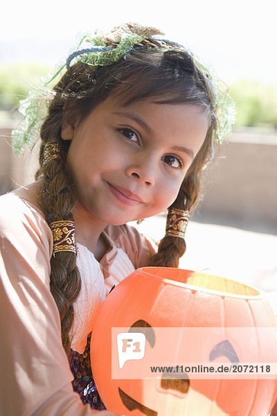Ein kleines als Prinzessin verkleidetes Mädchen mit einer Halloweenlaterne in der Hand