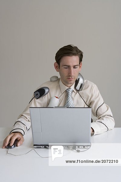 Ein Angestellter am Computer in Computerzubehör gewickelt